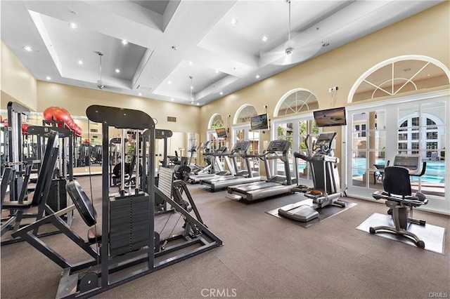 gym featuring french doors, a towering ceiling, and coffered ceiling