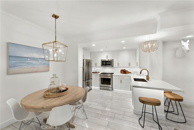 kitchen featuring pendant lighting, white cabinetry, backsplash, ornamental molding, and stainless steel appliances