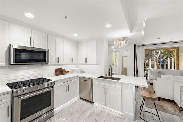 kitchen with sink, a breakfast bar, white cabinetry, stainless steel appliances, and kitchen peninsula