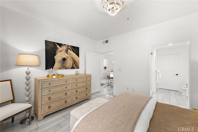 bedroom featuring ensuite bathroom and an inviting chandelier