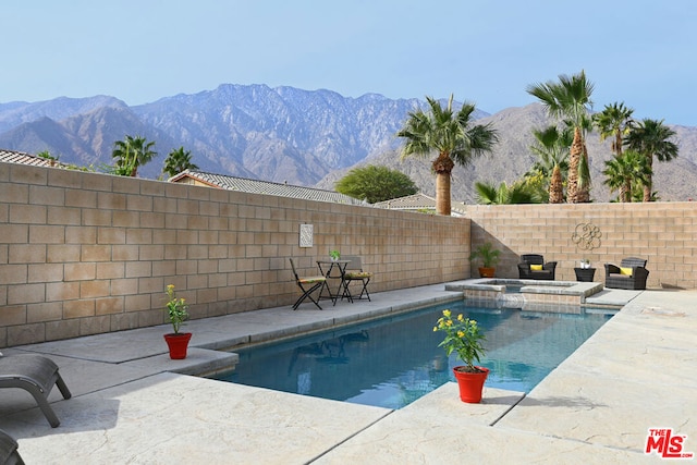 view of swimming pool featuring a mountain view, a patio area, and an in ground hot tub