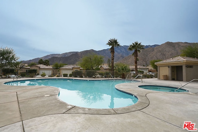 view of pool featuring a hot tub, a mountain view, and a patio area