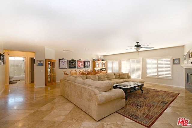 living room featuring a tiled fireplace and ceiling fan