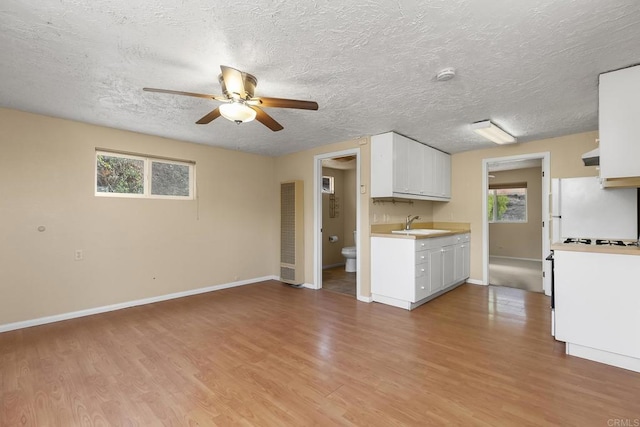 kitchen featuring sink, light hardwood / wood-style flooring, ceiling fan, white cabinetry, and white fridge