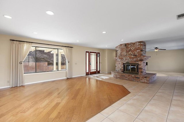 unfurnished living room featuring ceiling fan, a fireplace, and light hardwood / wood-style floors