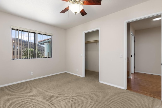 unfurnished bedroom with a spacious closet, light colored carpet, a mountain view, a closet, and ceiling fan