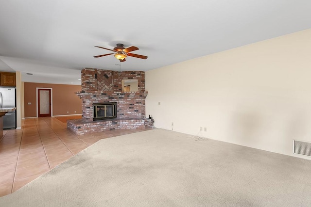 unfurnished living room featuring ceiling fan, light tile patterned floors, and a fireplace