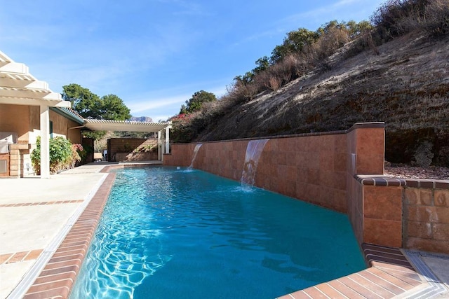 view of pool with pool water feature, a pergola, and a patio area