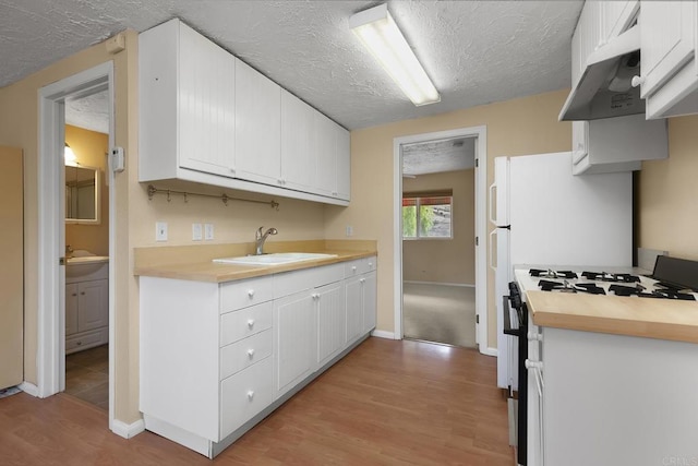 kitchen with white cabinetry, light hardwood / wood-style floors, range with gas stovetop, and sink