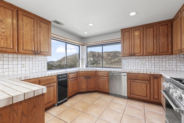 kitchen with a mountain view, tile countertops, decorative backsplash, and appliances with stainless steel finishes