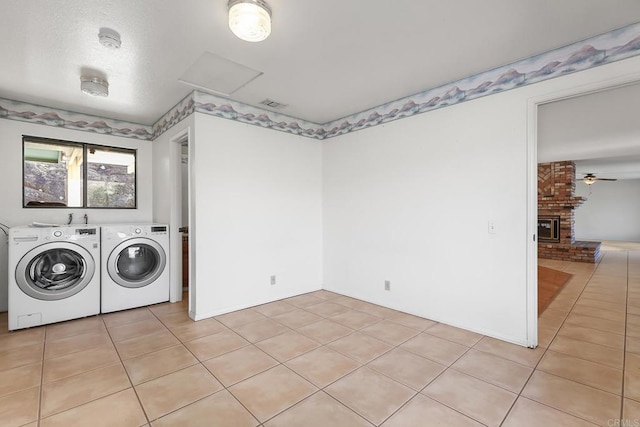 laundry room with ceiling fan, separate washer and dryer, light tile patterned floors, and a fireplace