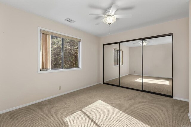 unfurnished bedroom featuring ceiling fan, light colored carpet, and a closet