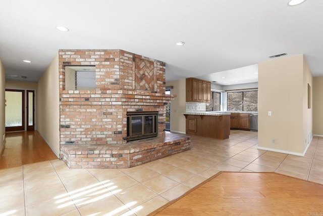 unfurnished living room with a brick fireplace and light tile patterned flooring