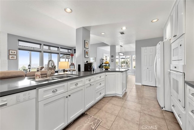 kitchen with sink, white appliances, white cabinetry, and kitchen peninsula