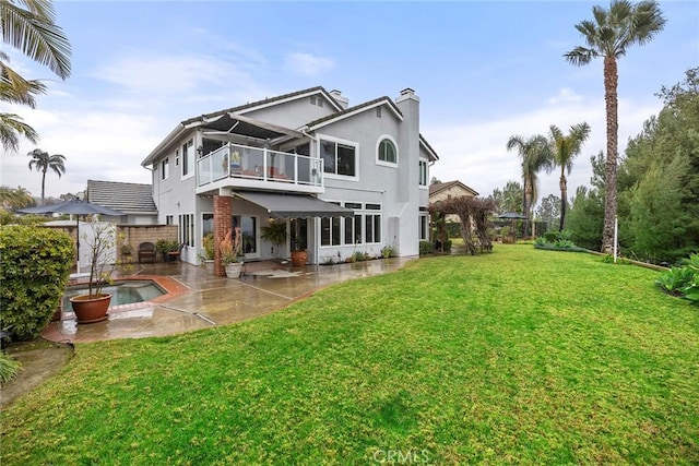 rear view of house with a yard, a balcony, a fenced in pool, and a patio area