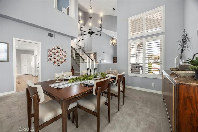 carpeted dining area with a notable chandelier and a high ceiling