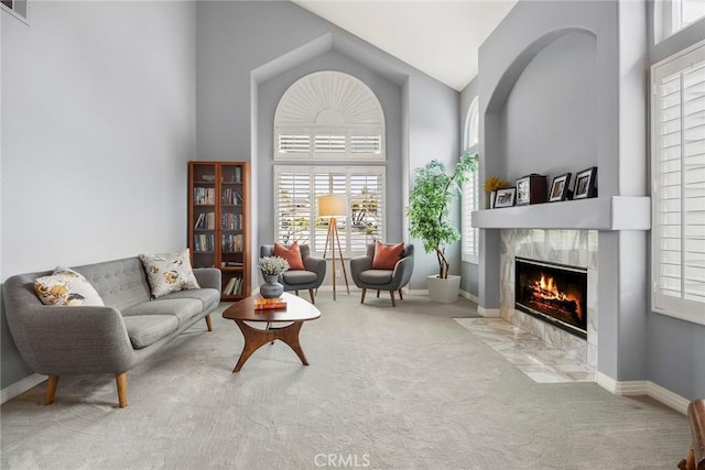 living room featuring high vaulted ceiling, a premium fireplace, and light colored carpet