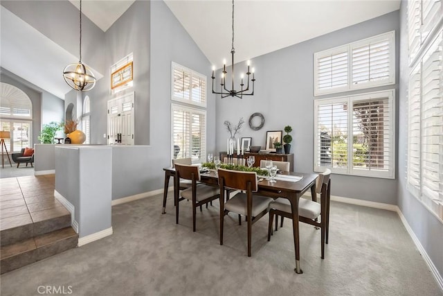 carpeted dining area with high vaulted ceiling and an inviting chandelier