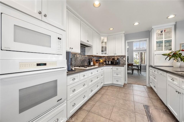 kitchen with light tile patterned floors, white appliances, tasteful backsplash, and white cabinets