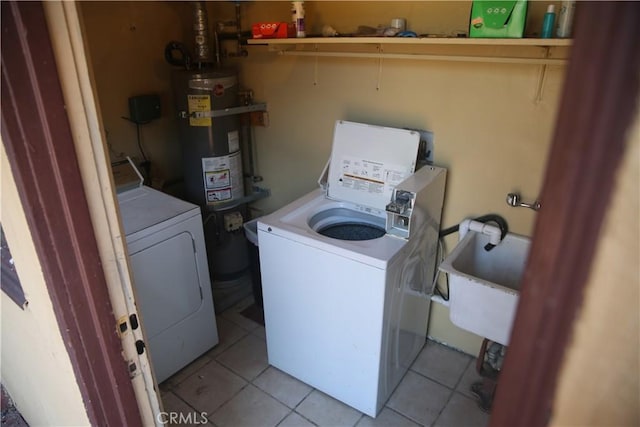 washroom with light tile patterned floors, gas water heater, washing machine and dryer, and sink