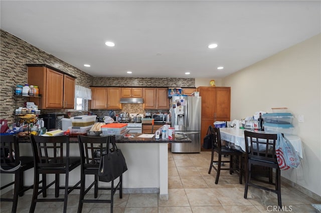 kitchen with light tile patterned floors, a breakfast bar, stainless steel appliances, tasteful backsplash, and a kitchen island