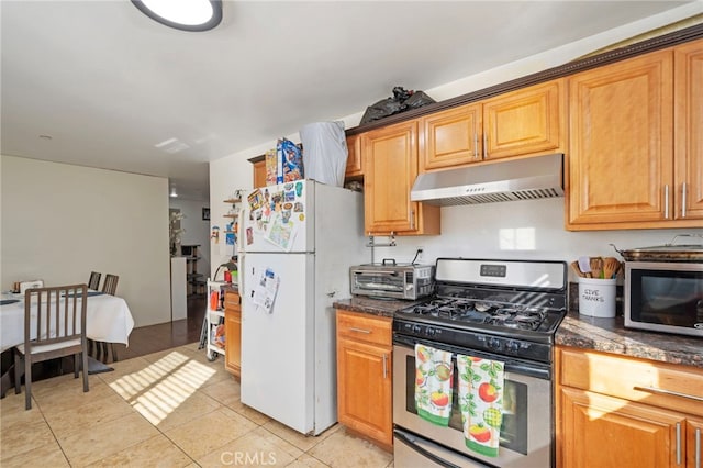 kitchen featuring dark stone countertops, appliances with stainless steel finishes, and light tile patterned floors