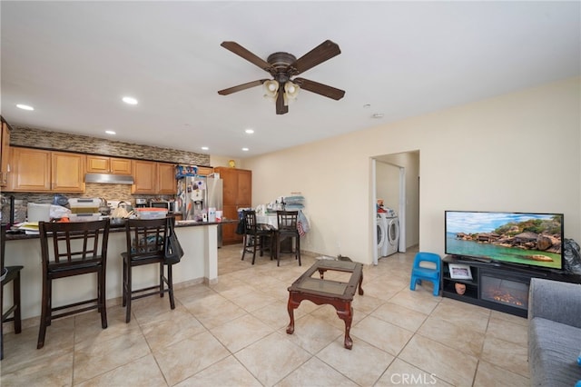 living room featuring ceiling fan, washing machine and clothes dryer, and light tile patterned floors