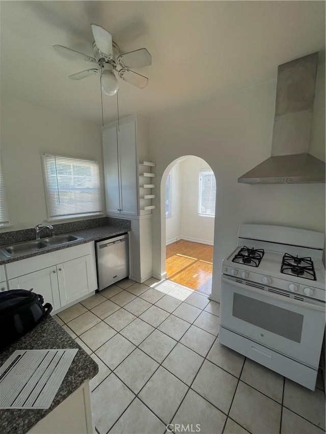 kitchen with sink, white cabinets, stainless steel dishwasher, white gas stove, and wall chimney exhaust hood