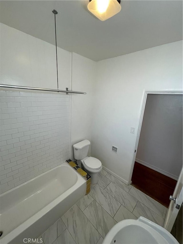 bathroom with tiled shower / bath combo and toilet