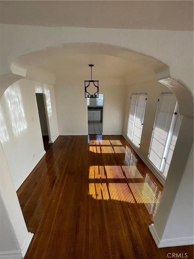 unfurnished living room with a notable chandelier and dark hardwood / wood-style flooring