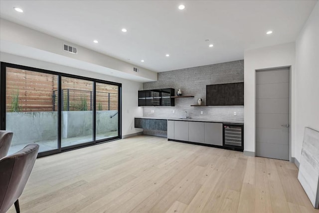 kitchen with decorative backsplash, sink, wine cooler, and light hardwood / wood-style flooring