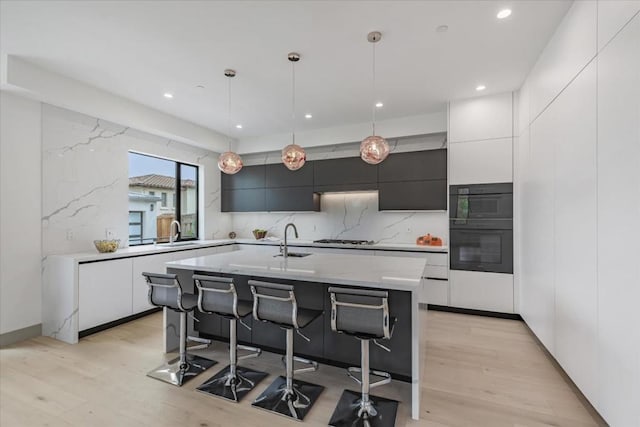 kitchen featuring pendant lighting, stainless steel gas stovetop, sink, a breakfast bar area, and a kitchen island with sink