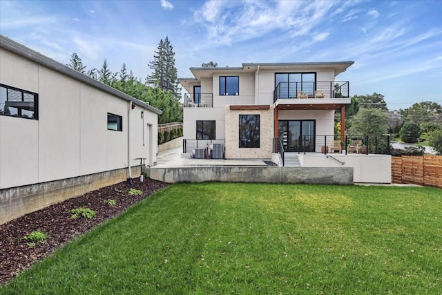 rear view of house with a balcony, a patio area, and a lawn