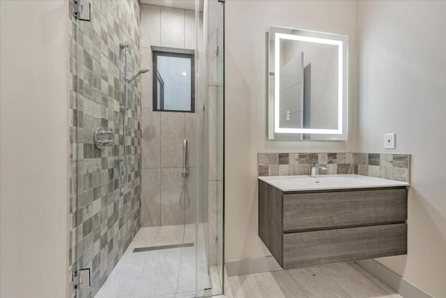 bathroom featuring vanity, a shower with door, and decorative backsplash