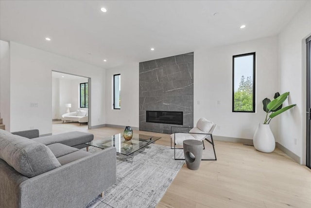 living room with a premium fireplace, a wealth of natural light, and light wood-type flooring