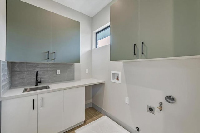 laundry area with sink, electric dryer hookup, hookup for a washing machine, cabinets, and light wood-type flooring