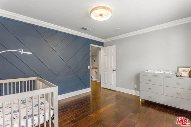 bedroom featuring crown molding, dark wood-type flooring, and a nursery area