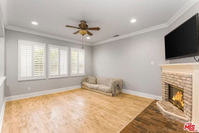 unfurnished room with crown molding, ceiling fan, hardwood / wood-style floors, and a brick fireplace