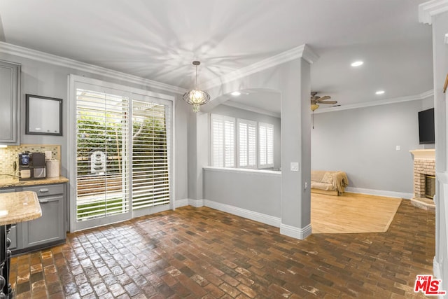 unfurnished dining area with a fireplace, ornamental molding, and ceiling fan