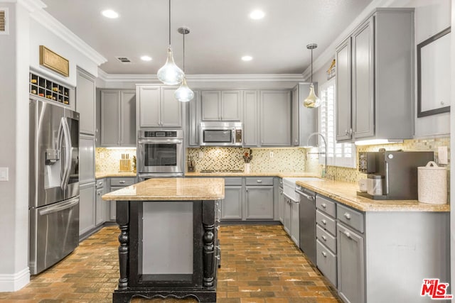 kitchen featuring gray cabinets, sink, hanging light fixtures, ornamental molding, and stainless steel appliances