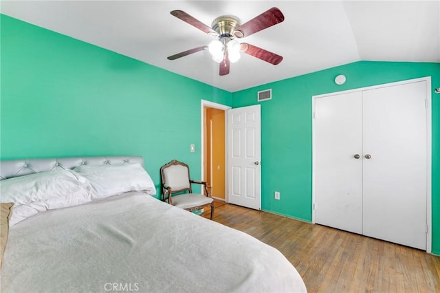 bedroom featuring lofted ceiling, hardwood / wood-style floors, ceiling fan, and a closet