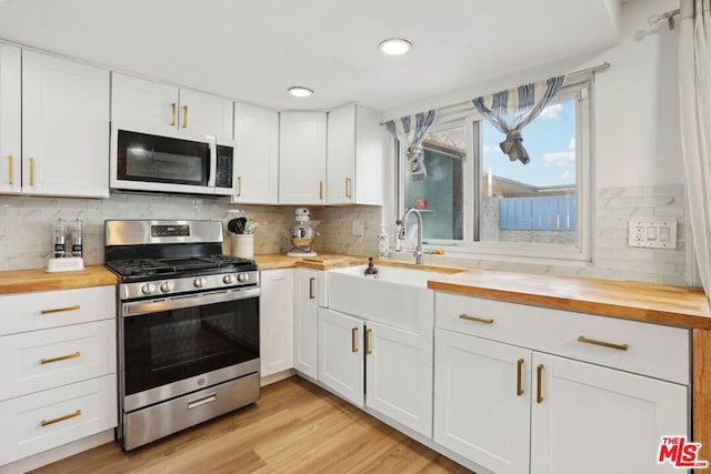 kitchen featuring white cabinetry, stainless steel gas range oven, and wood counters