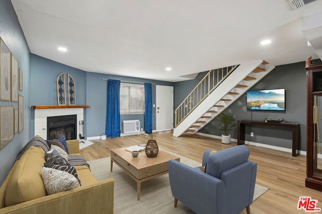 living room featuring a wall mounted AC and light hardwood / wood-style floors