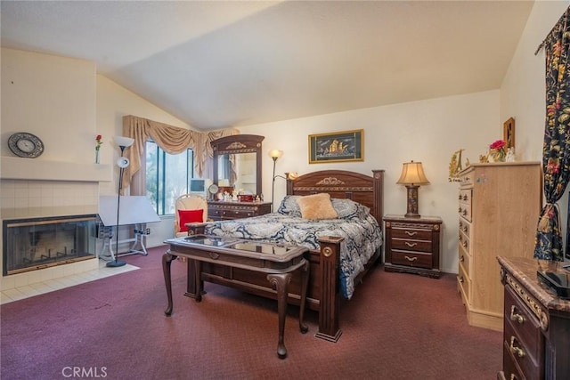 carpeted bedroom featuring vaulted ceiling and a tile fireplace