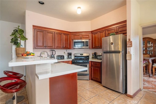 kitchen with light tile patterned flooring, stainless steel appliances, kitchen peninsula, and a kitchen bar