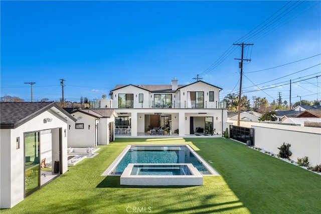 rear view of house with a yard, a patio area, and an in ground hot tub