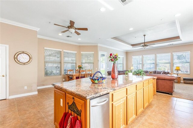 kitchen with open floor plan, ceiling fan, a raised ceiling, and a center island with sink