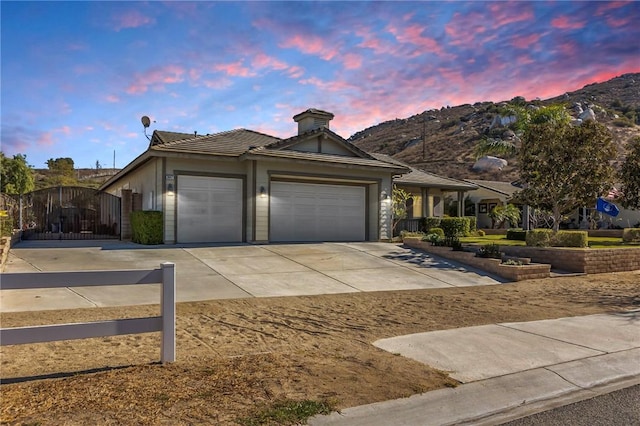 ranch-style home with a garage, concrete driveway, a mountain view, and a gate