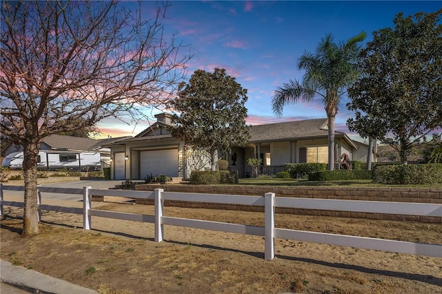 single story home featuring a garage, concrete driveway, and a fenced front yard