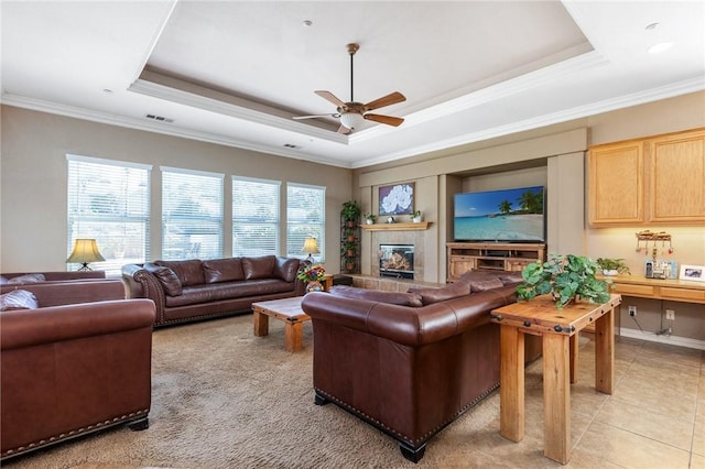 living area featuring light tile patterned floors, a tray ceiling, a tiled fireplace, and visible vents